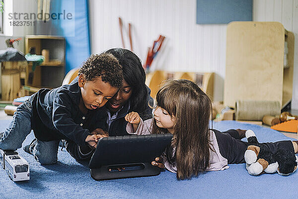 Lehrerin teilt digitales Tablet mit Kindern in der Kindertagesstätte