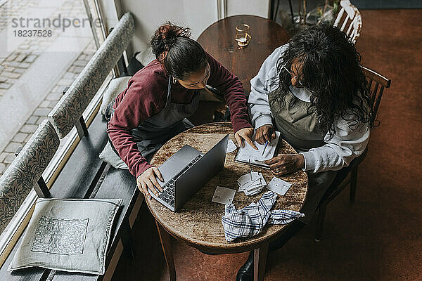 Hohe Winkel Ansicht der weiblichen Café Besitzer diskutieren über Tagebuch beim Sitzen am Tisch in Kaffee chop