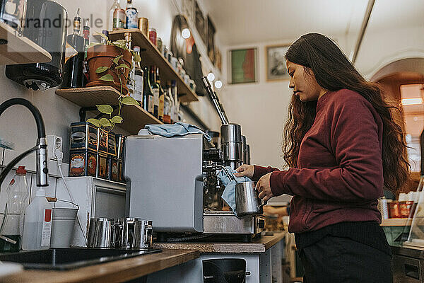 Seitenansicht einer Unternehmerin beim Kaffeekochen in einem Café