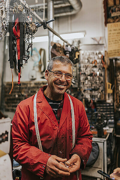 Porträt eines fröhlichen männlichen Schlossers mit Brille in einer Werkstatt