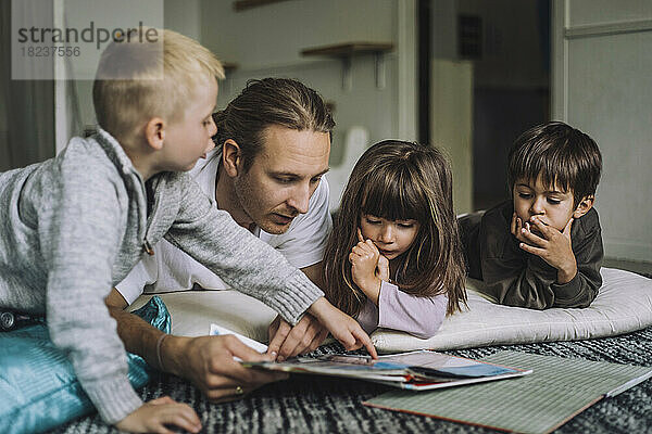 Männlicher Kinderbetreuer liest Kindern im Kindergarten ein Buch vor