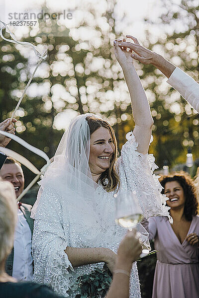 Glückliches frisch verheiratetes Paar tanzt inmitten von Familie und Freunden bei der Hochzeit