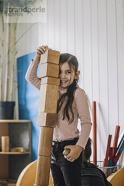 Lächelndes Mädchen stapelt Holzklötze im Kindergarten