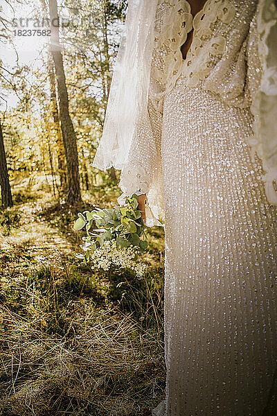 Midsection von Mitte Erwachsenen Braut trägt weißes Hochzeitskleid im Wald