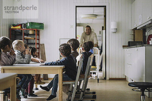 Männliche und weibliche Schüler verschiedener Rassen sitzen beim Frühstück im Kindergarten am Esstisch