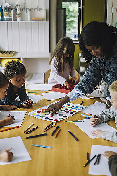 Lehrerin  die Schülern im Kindergarten das Erkennen von Farben beibringt