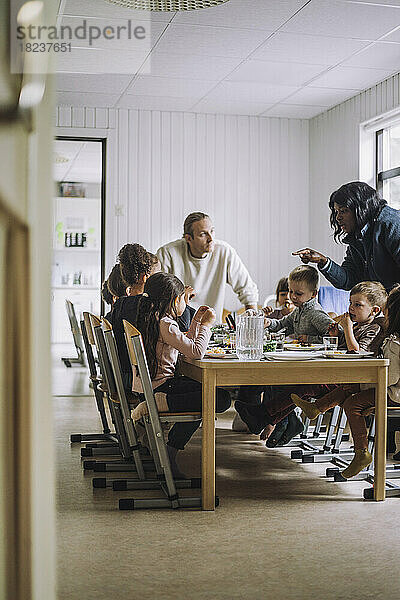 Lehrerinnen und Lehrer im Gespräch mit Kindern beim Frühstück am Esstisch