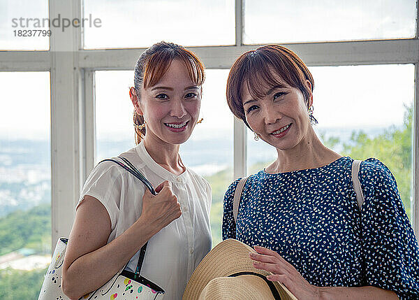 Zwei reife japanische Frauen  Freundinnen  Seite an Seite  an einem Tagesausflug  blickend in die Kamera.