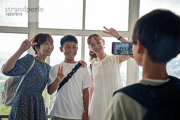 Ein Junge fotografiert mit seinem Mobiltelefon drei Japaner  einen 13-jährigen Jungen  seine Mutter und einen Freund.