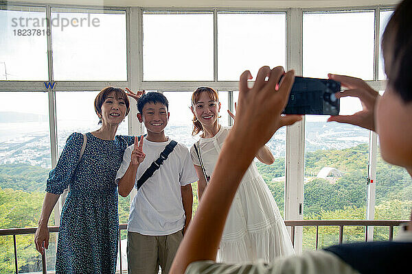 Ein Junge fotografiert mit seinem Mobiltelefon drei Personen  einen 13-jährigen Jungen  seine Mutter und einen Freund.