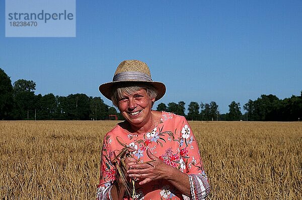 Porträt  Frau  weiblich  draußen  eine Frau mit Strohhut steht in einem Getreidefeld