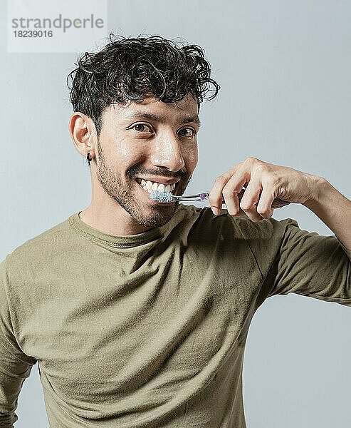 Lächelnder Mann  der sich die Zähne putzt  Gesicht eines gutaussehenden Mannes  der sich die Zähne putzt. Zähneputzen und Pflege Konzept. Gesicht eines Mannes  isoliert. Oral und Zahn Lächeln Konzept