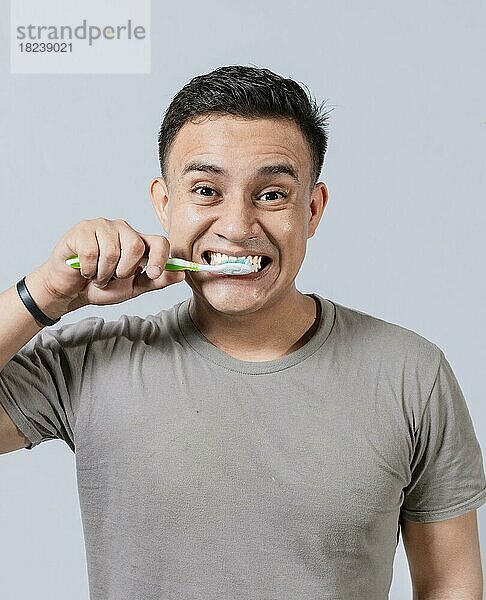 Gesicht eines gutaussehenden Mannes  der sich die Zähne putzt. Zähneputzen und Pflege Konzept. Gesicht eines Mannes  der sich die Zähne putzt  isoliert. Oral und zahnärztliche Lächeln Konzept  Lächelnder Mann putzt seine Zähne isoliert
