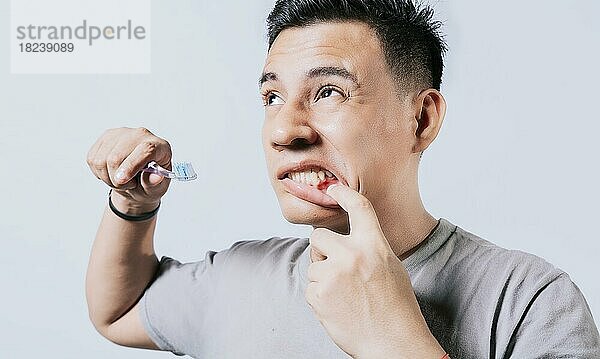 Mann hält Zahnbürste mit Zahnfleischschmerzen isoliert  Menschen halten Zahnbürste mit Zahnfleischproblem isoliert. Junger Mann mit Zahnfleischentzündung hält Zahnbürste  Menschen halten Zahnbürste mit Zahnfleischschmerzen