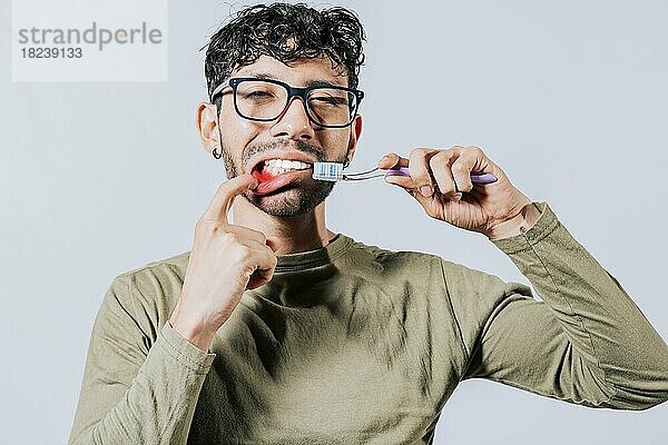 Mann hält Zahnbürste mit Zahnfleischschmerzen  Menschen halten Zahnbürste mit Zahnfleischproblem isoliert. Junger Mann mit Zahnfleischentzündung hält Zahnbürste. Menschen halten Zahnbürste mit Zahnfleischschmerzen