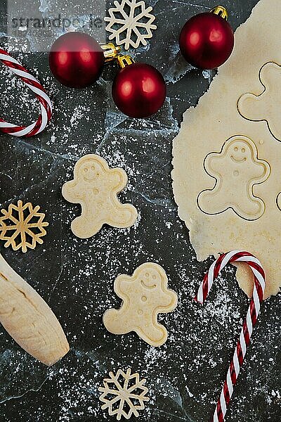 Overhead flach legen Konzept für das Backen von Weihnachtsplätzchen mit ausgerollten Plätzchenteig  Kekse in Form von glücklichen Lebkuchenmänner und saisonale Dekoration auf dunklem Marmor Hintergrund