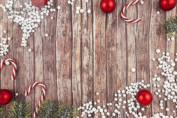 Saisonale Weihnachten flach legen mit traditionellen roten Baumschmuck Kugeln  weiße Schneekugeln  Zuckerstangen und Tannenzweige auf leeren hölzernen Kopie Raum Hintergrund