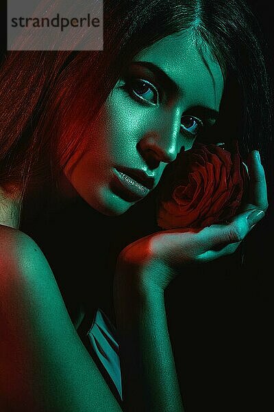 Schönes Mädchen mit einer Rose in der Hand. Die Schönheit des Gesichts. Porträtaufnahme im Studio mit Farbfiltern