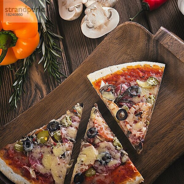 Aufgeschnittene leckere frische Pizza mit Pilzen und Wurst auf einem hölzernen Hintergrund. Ansicht von oben. Nahaufnahme