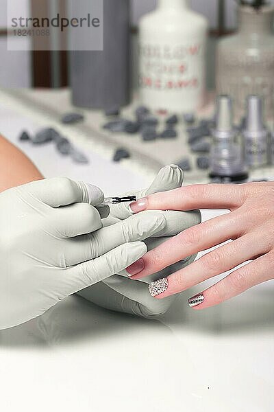 Closeup Fingernagelpflege durch Maniküre Spezialist in Schönheitssalon. Maniküre malt Nägel mit Nagellack