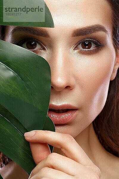 Schöne frische Frau mit perfekter Haut  natürliches Make-up und grüne Blätter. Schönes Gesicht. Foto im Studio aufgenommen