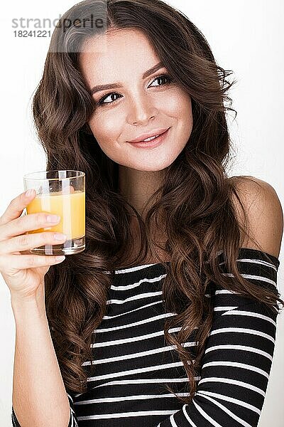 Schöne Frau mit gesunder Haut  lockigem Haar und Orangensaft posiert im Studio. Schönheit Gesicht