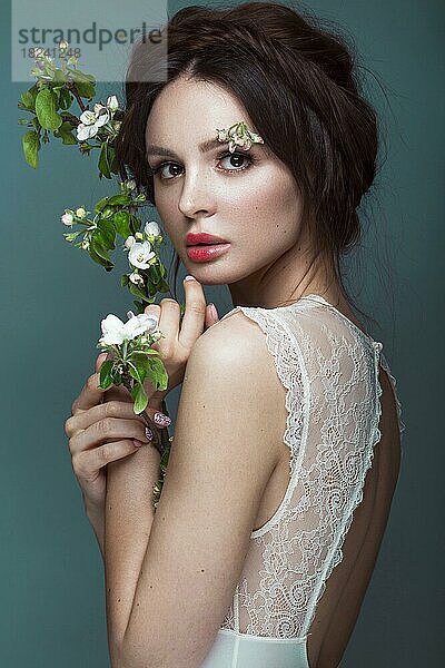 Schöne brünette Mädchen in Dessous mit einem sanften romantischen Make-up  rosa Lippen  hält Blumen. Die Schönheit des Gesichts. Porträtaufnahme im Studio