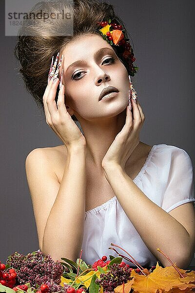 Schönes Mädchen im Herbst Bild mit langen Nägeln mit hellen und ungewöhnlichen Make-up. Bild im Studio auf einem grauen Hintergrund genommen