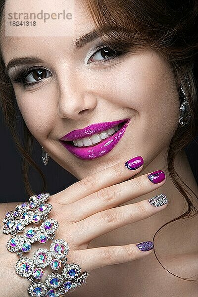 Schönes Mädchen mit einem hellen Abend Make-up und lila Maniküre mit Strasssteinen. Nageldesign. Schönheit Gesicht. Bild im Studio auf einem schwarzen Hintergrund genommen