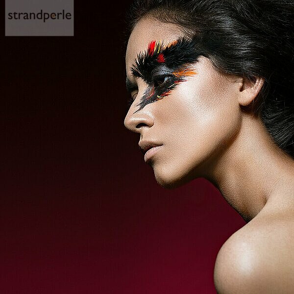 Schönes Mädchen im Bild des Phönixvogels mit kreativem Make-up  die Schönheit des Gesichts. Fotos im Studio geschossen