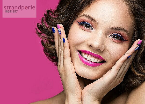 Schönes Modell Mädchen mit hellen Make-up  Lächeln und farbigen Nagellack. Schönes Gesicht. Kurze bunte Nägel. Bild im Studio auf einem rosa Hintergrund genommen