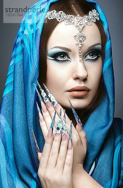 Schönes Mädchen im östlichen Arabisch Bild mit langen Nägeln und hellblau Make-up. Bild im Studio auf einem grauen Hintergrund genommen