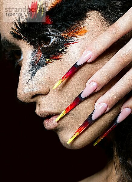 Schönes Mädchen im Bild des Phoenix-Vogels mit kreativem Make-up und langen Nägeln. Maniküre Design. Die Schönheit des Gesichts. Fotos im Studio geschossen