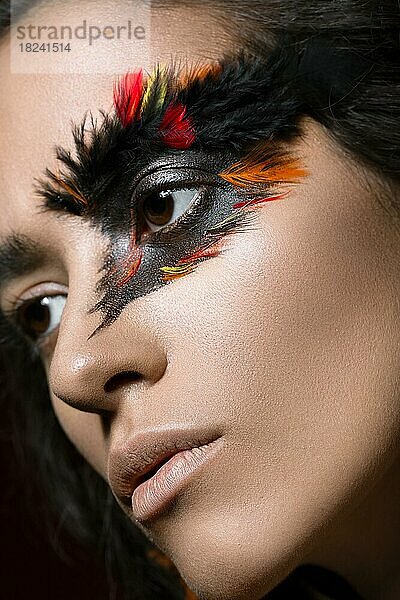 Schönes Mädchen im Bild des Phönixvogels mit kreativem Make-up  die Schönheit des Gesichts. Fotos im Studio geschossen