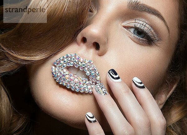 Schönes Mädchen mit hellen Nägeln und Lippen aus Kristallen  langen Wimpern und Locken. Schönes Gesicht. Bild in einem Studio aufgenommen