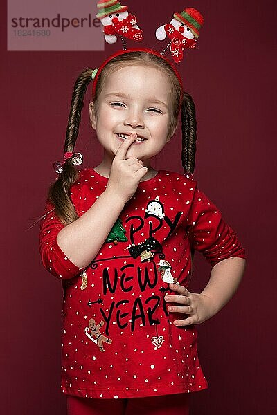Lustiges kleines Mädchen im Neujahrsbild  das verschiedene Emotionen zeigt. Foto im Studio aufgenommen