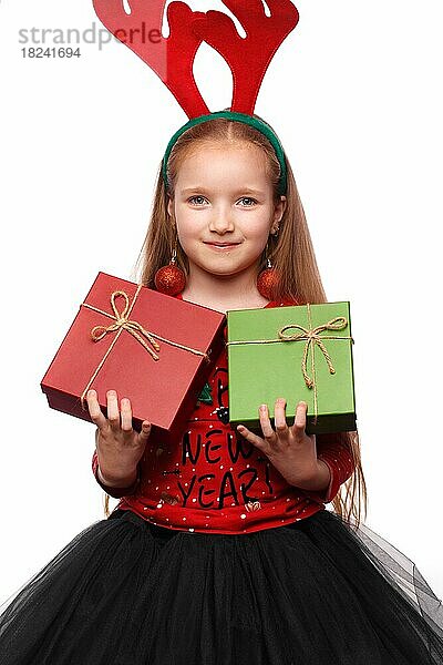 Hübsches kleines Mädchen in einem Neujahrsbild mit Kisten voller Geschenke in den Händen und Hirschhörnern auf dem Kopf. Foto im Studio aufgenommen