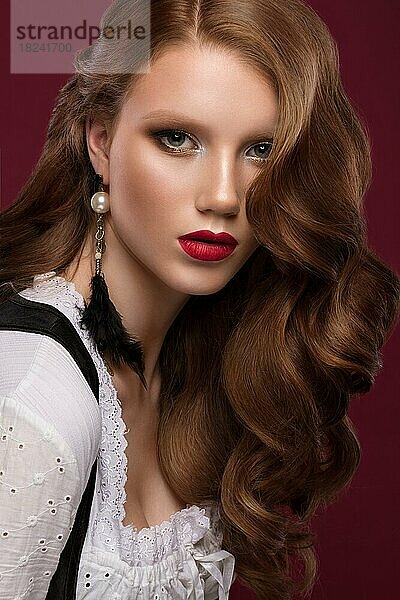 Schönes rothaariges Modell: Locken  helles Make-up  Schmuck und rote Lippen. Das Schönheitsgesicht. Porträtaufnahme im Studio auf einem braunen Hintergrund