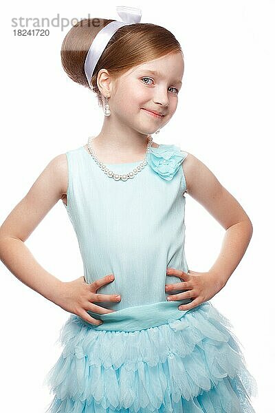Ein kleines Mädchen in einem blauen Kleid  mit einer Retro-Frisur und Accessoires. Foto im Studio aufgenommen