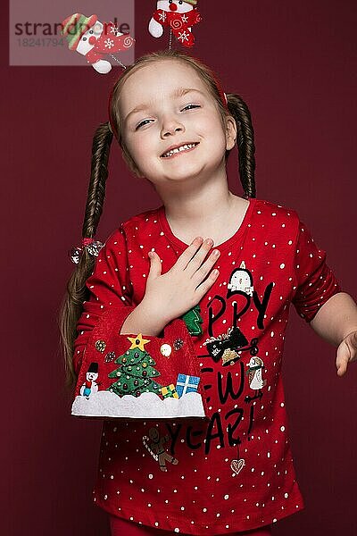 Lustiges kleines Mädchen im Neujahrsbild  das verschiedene Emotionen zeigt. Foto im Studio aufgenommen