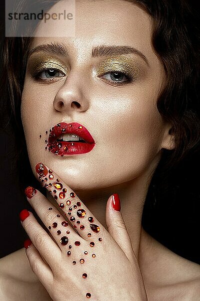 Schönes Mädchen mit Abend-Make-up  rote Lippen in Strass und Design Maniküre Nägel. Schönheit Gesicht. Fotos im Studio geschossen