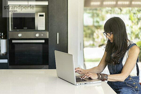 Geschäftsfrau  die von zu Hause aus arbeitet und auf einen Laptop schaut. Selbstbewusste Frau mit Laptop