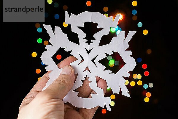 Schneeflocke geformt Papier in der Hand auf Bokeh Licht Hintergrund