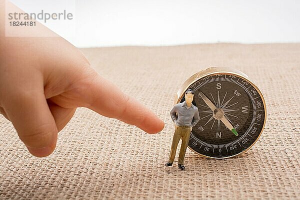 Figurine Mann neben einem Kompass auf Leinwand