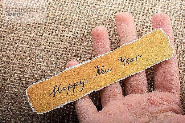 Frohes neues Jahr  geschrieben auf einem zerrissenen gelben Papier in der Hand