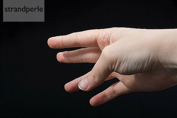 Fünf Finger einer Kinderhand teilweise in schwarzem Hintergrund zu sehen