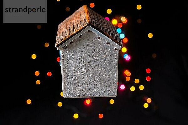 Kleines Modellhaus auf einem Bokeh-Licht vor einem dunklen Hintergrund