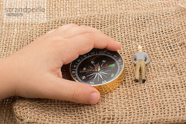 Hand hält einen Kompass neben einer Figur