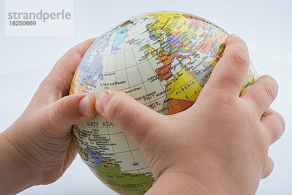 Kind hält einen Globus in einem Kreis aus zerknülltem Papier
