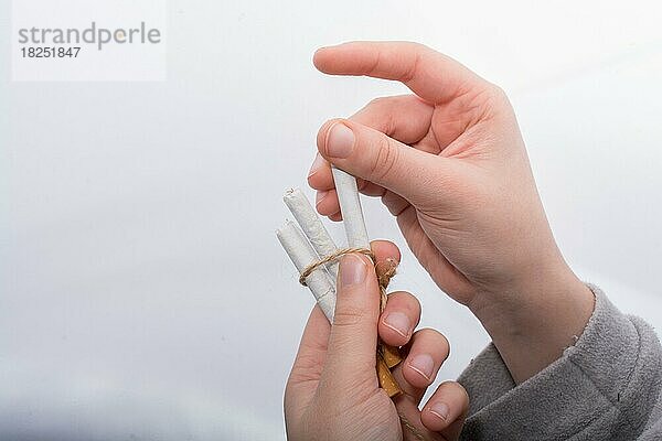 Hand hält Bündel von Zigaretten auf weißem Hintergrund